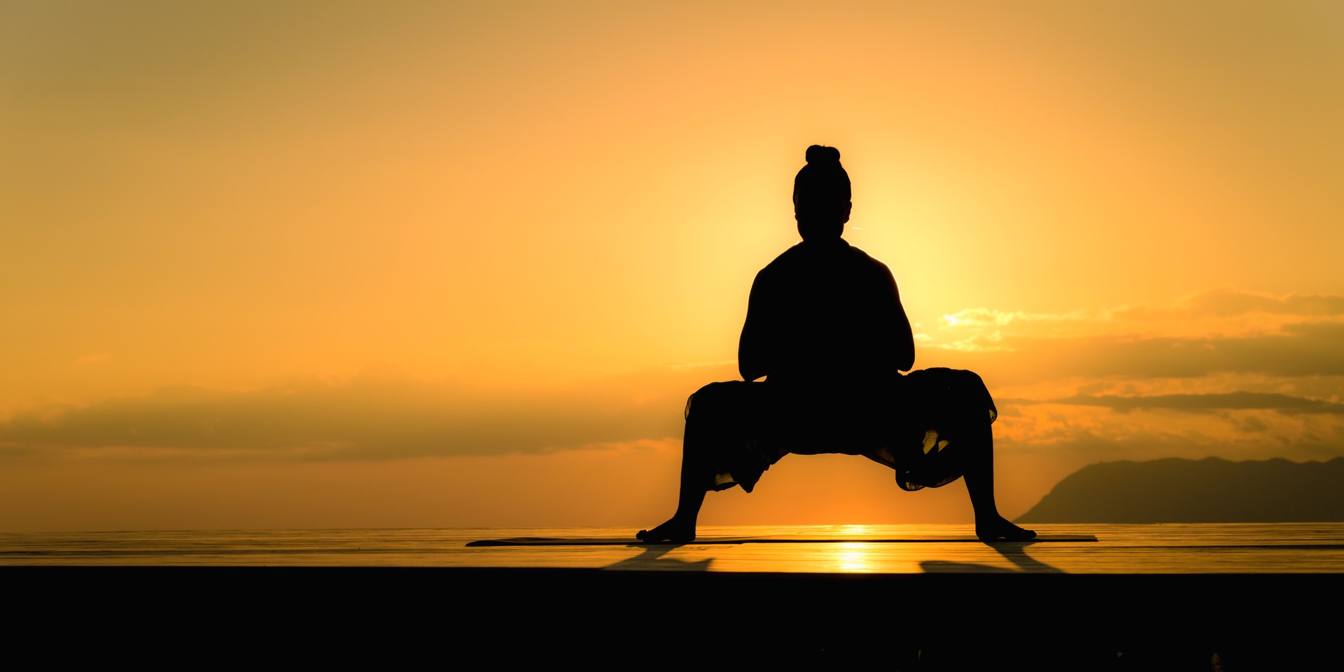Woman silhouette practicing garland asana, doing yoga